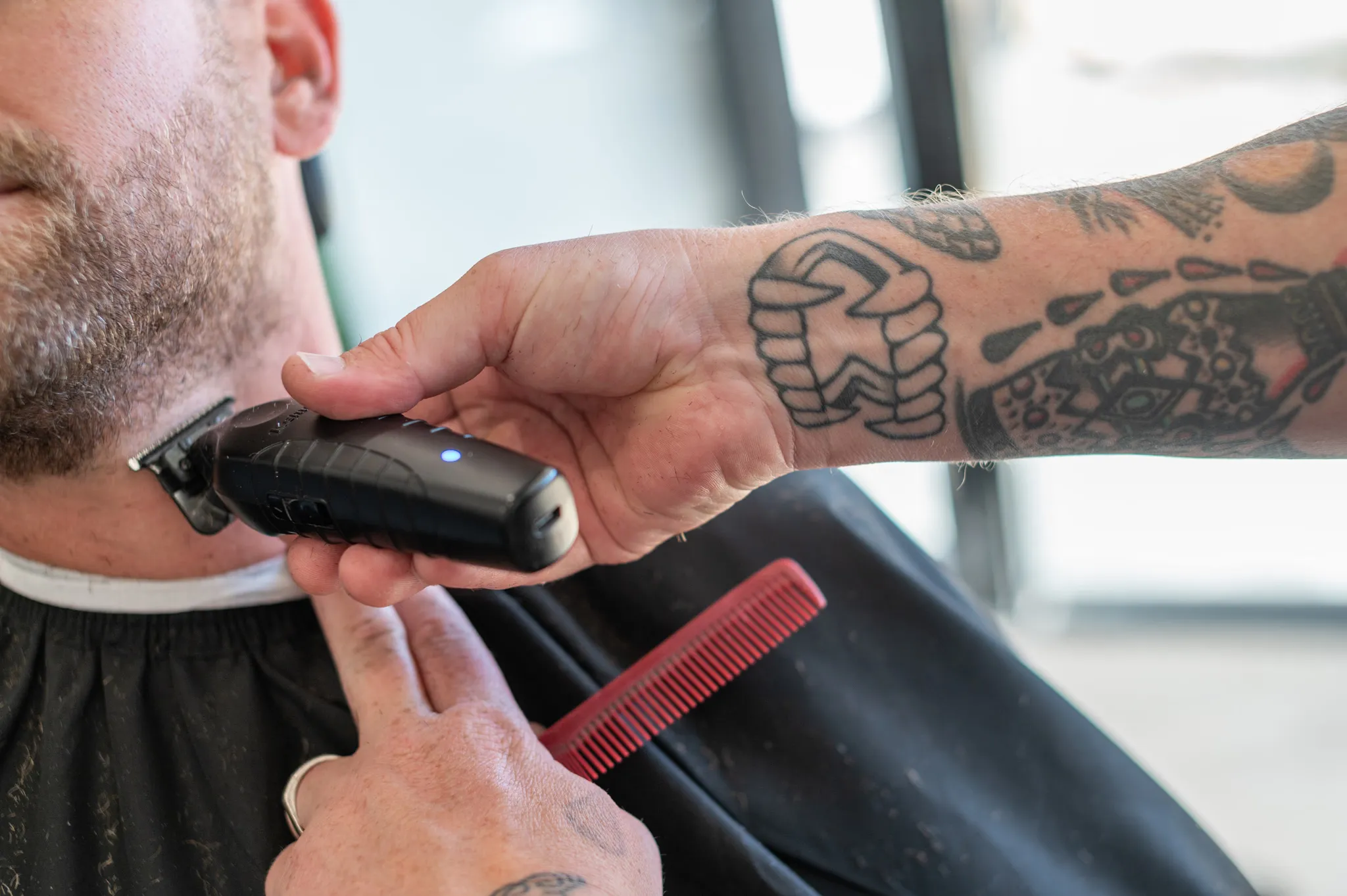 Barber detailing a beard line-up with a trimmer