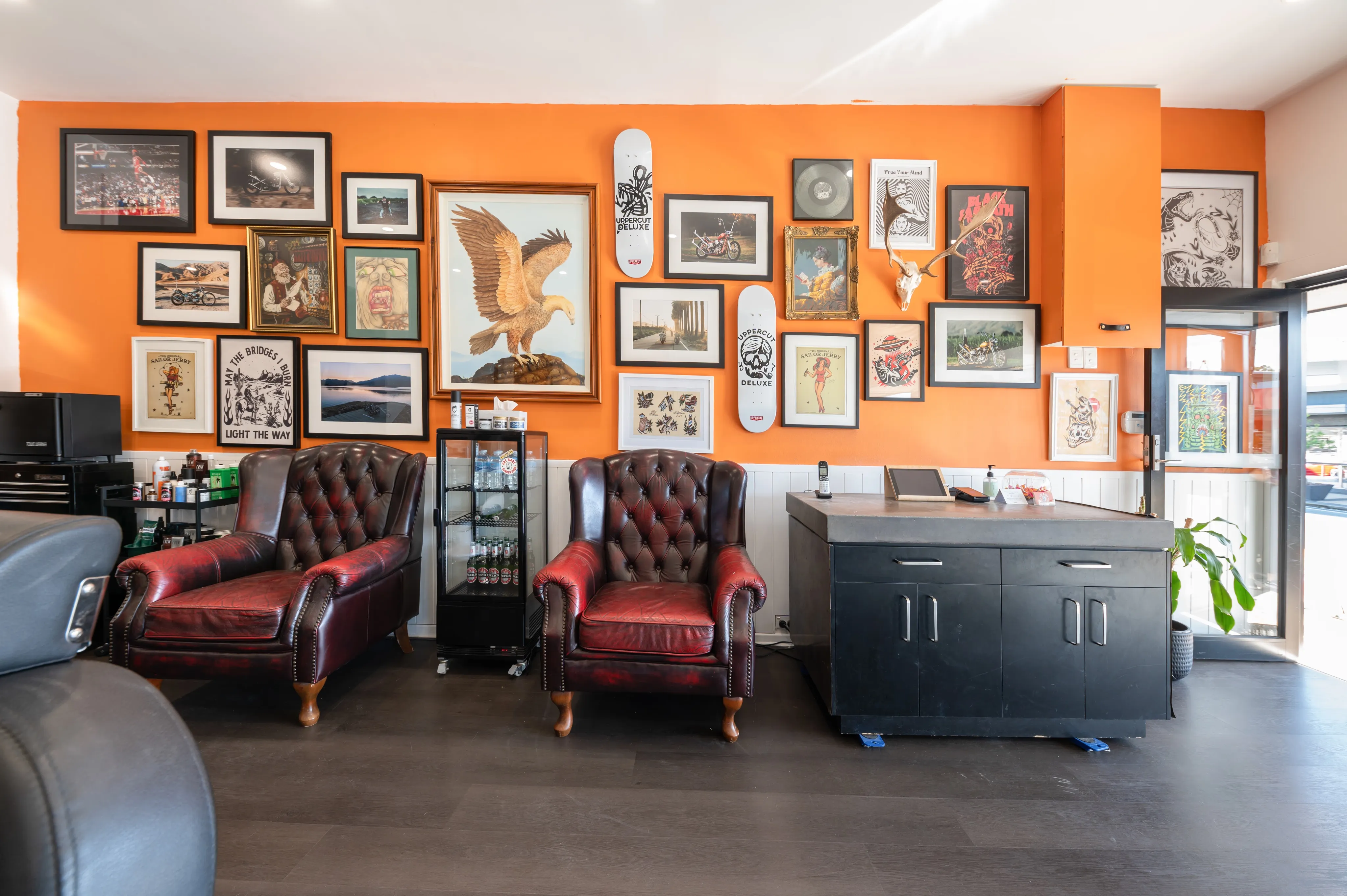 Chesterfield armchairs against the orange gallery wall inside the shop